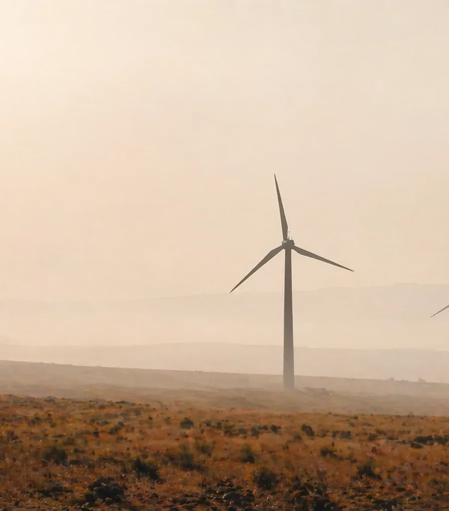 Three wind turbines silhouetted on a hazy plateau