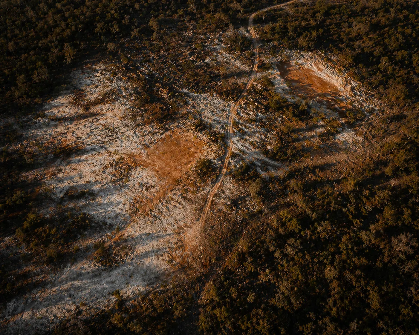 Aerial view of the Sakania miombo plateau — exposed bedrock scars and a single survey track